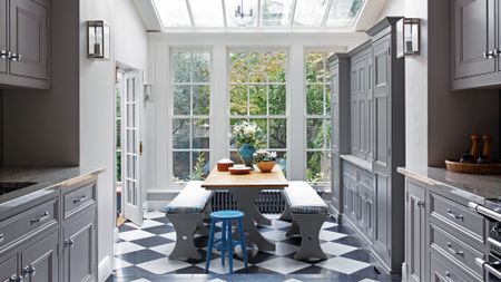 A kitchen with checkered grey and white floors with grey cabinets