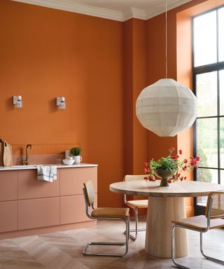 White hanging lamp, wooden table, orange walls