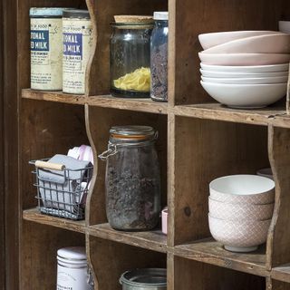 wooden cupboard with white bowls and glass jars with food items