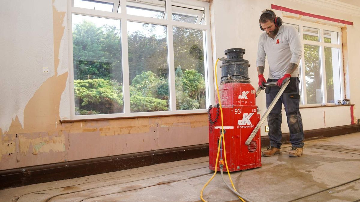 Man channelling out underfloor heating channels, ready to take underfloor heating pipes, in a concrete subfloor