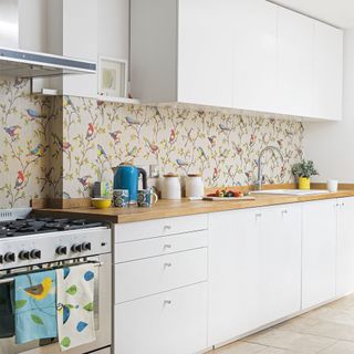 A white kitchen with a wallpapered splashback