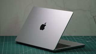 MacBook Pro de 14 pulgadas (2023) con la tapa a medio cerrar y mostrando el logo de Apple