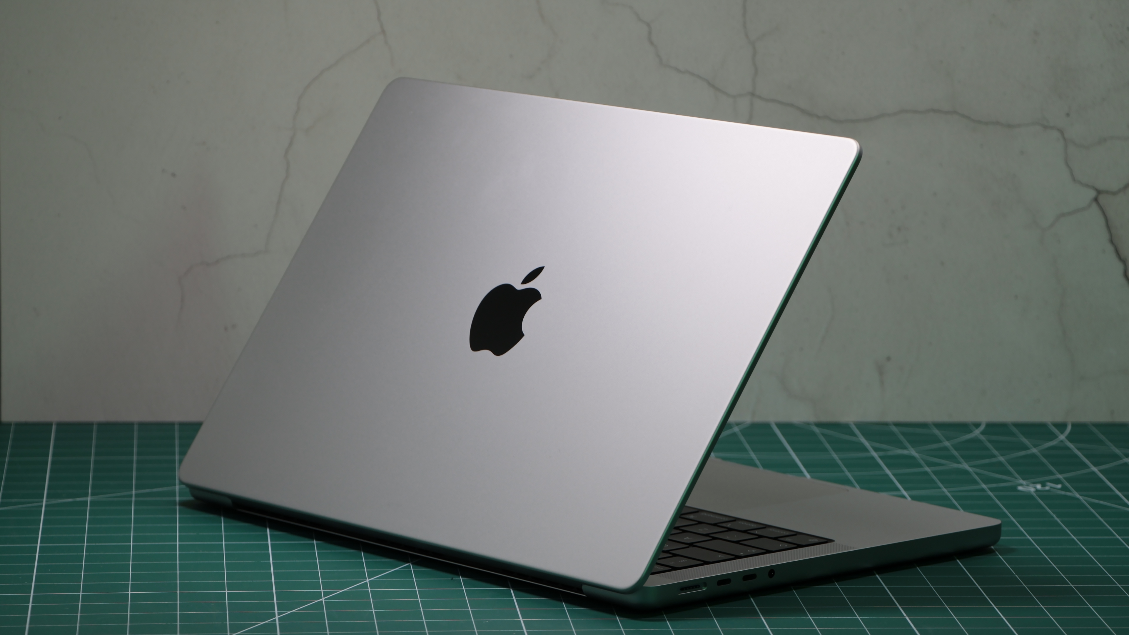 MacBook Pro 14- дюйм (2023 г.) в студии с частично закрытой крышкой, на которой виден логотип Apple
