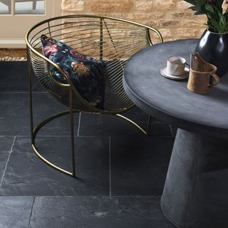 room with golden chair cushion and black slate tiles