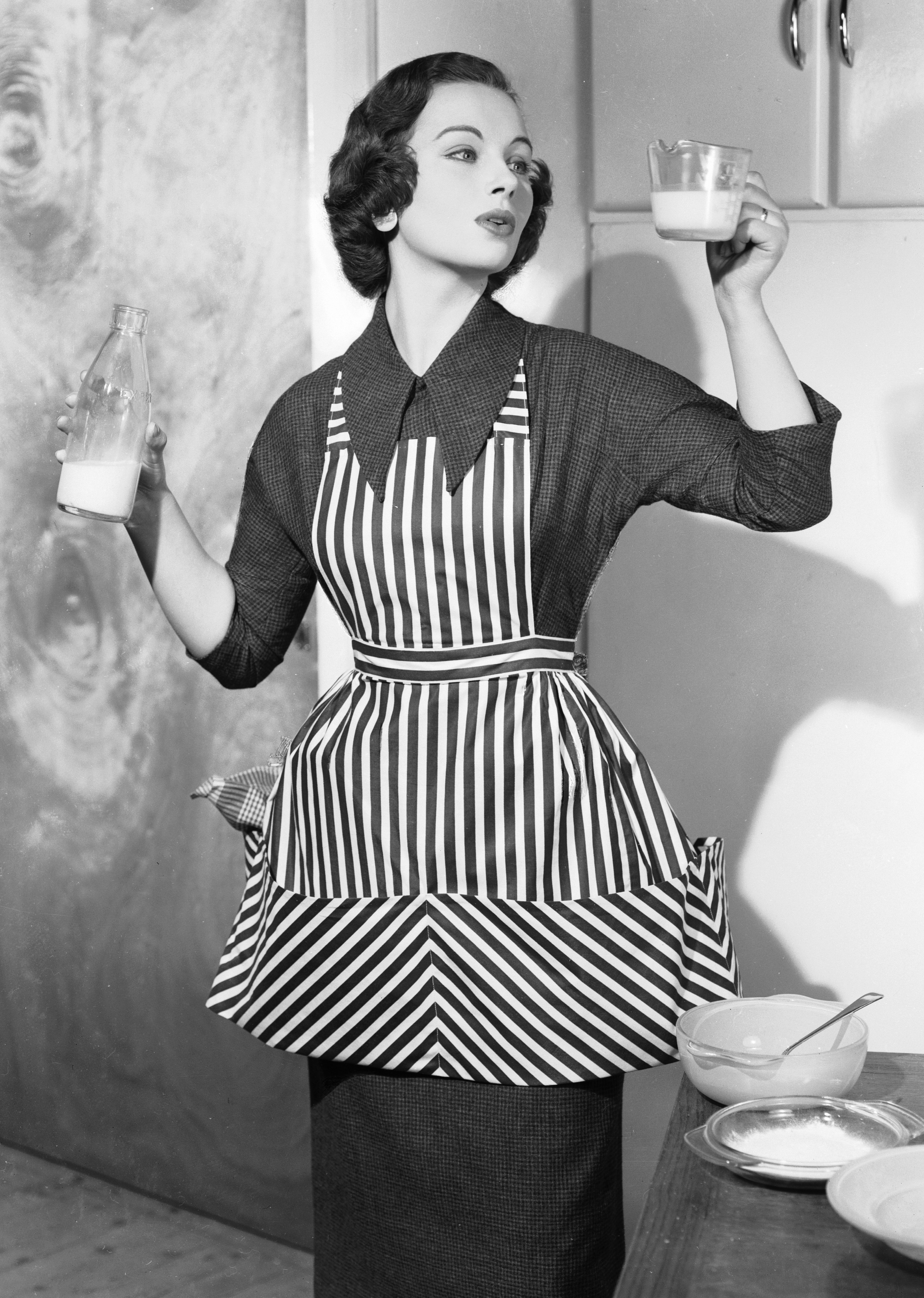 24th February 1956: A woman pours milk into a measuring jug whilst cooking. (Photo by Chaloner Woods/Getty Images)