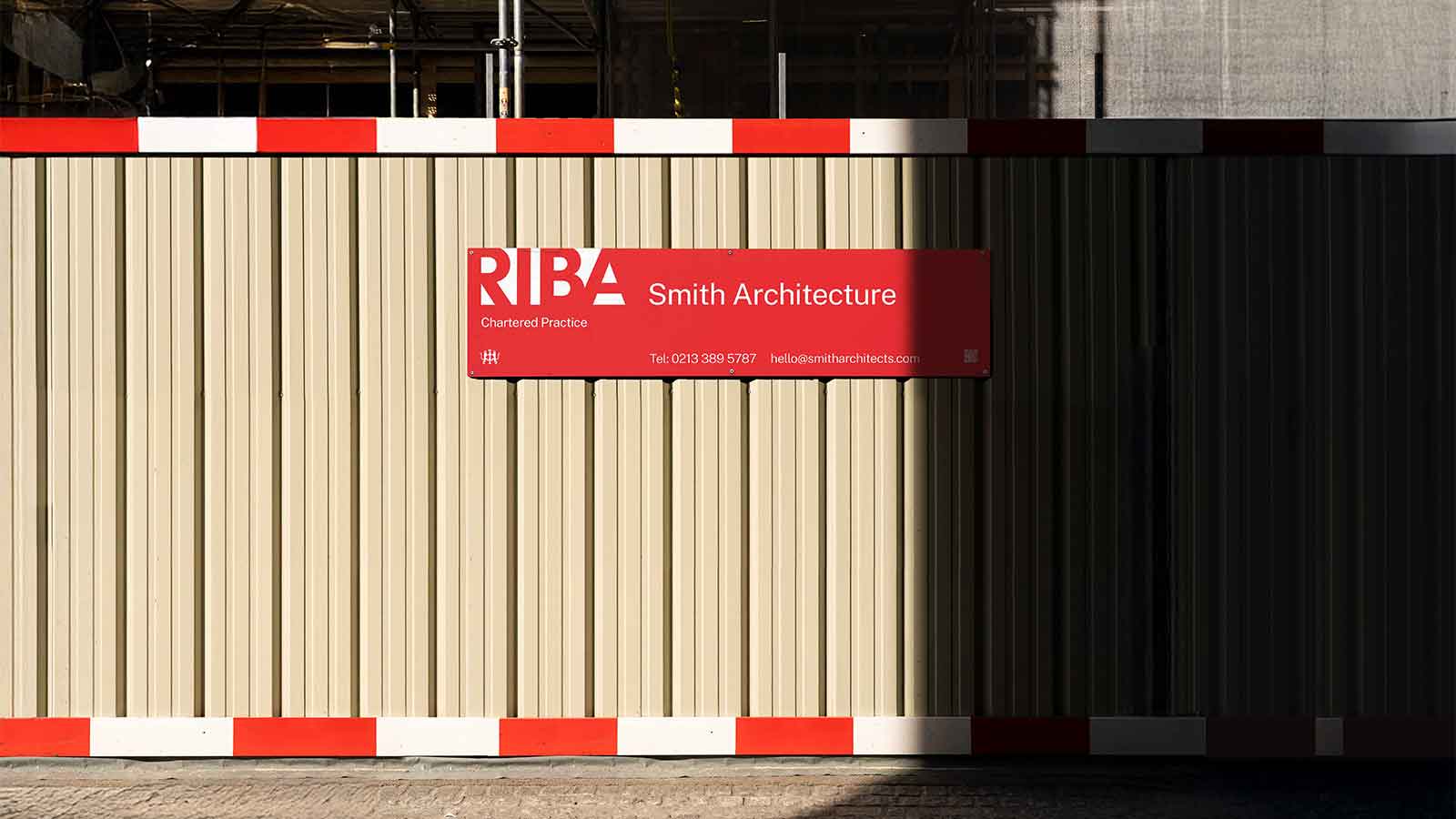 On a scaffolding covering a building site is a red sign with upper case lettering spelling RIBA in bold red type over a white background