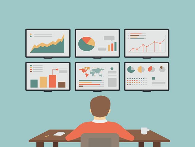 Man sitting at a desk looking at six monitors displaying graphs