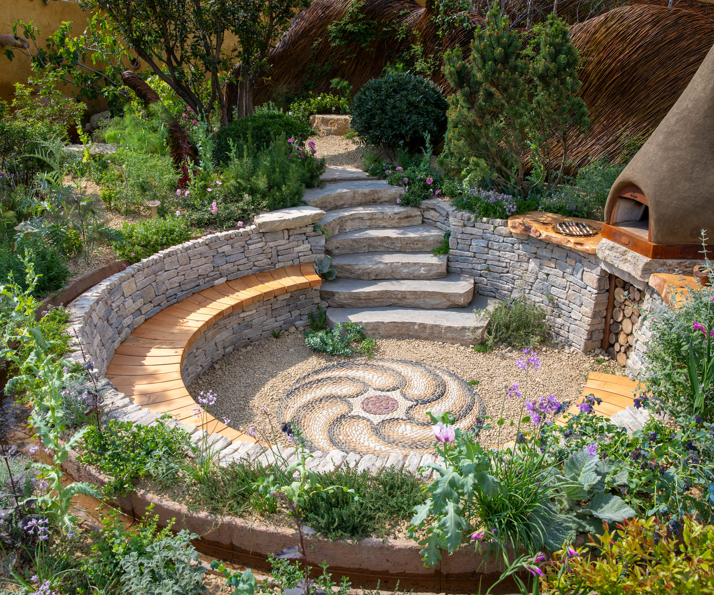 sunken circular patio with garden steps, bench seat and planting