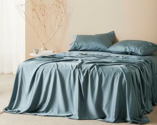 Mid blue silky bed sheets draped on bed