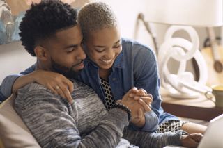 Happy couple holding hands while sitting on bed at home