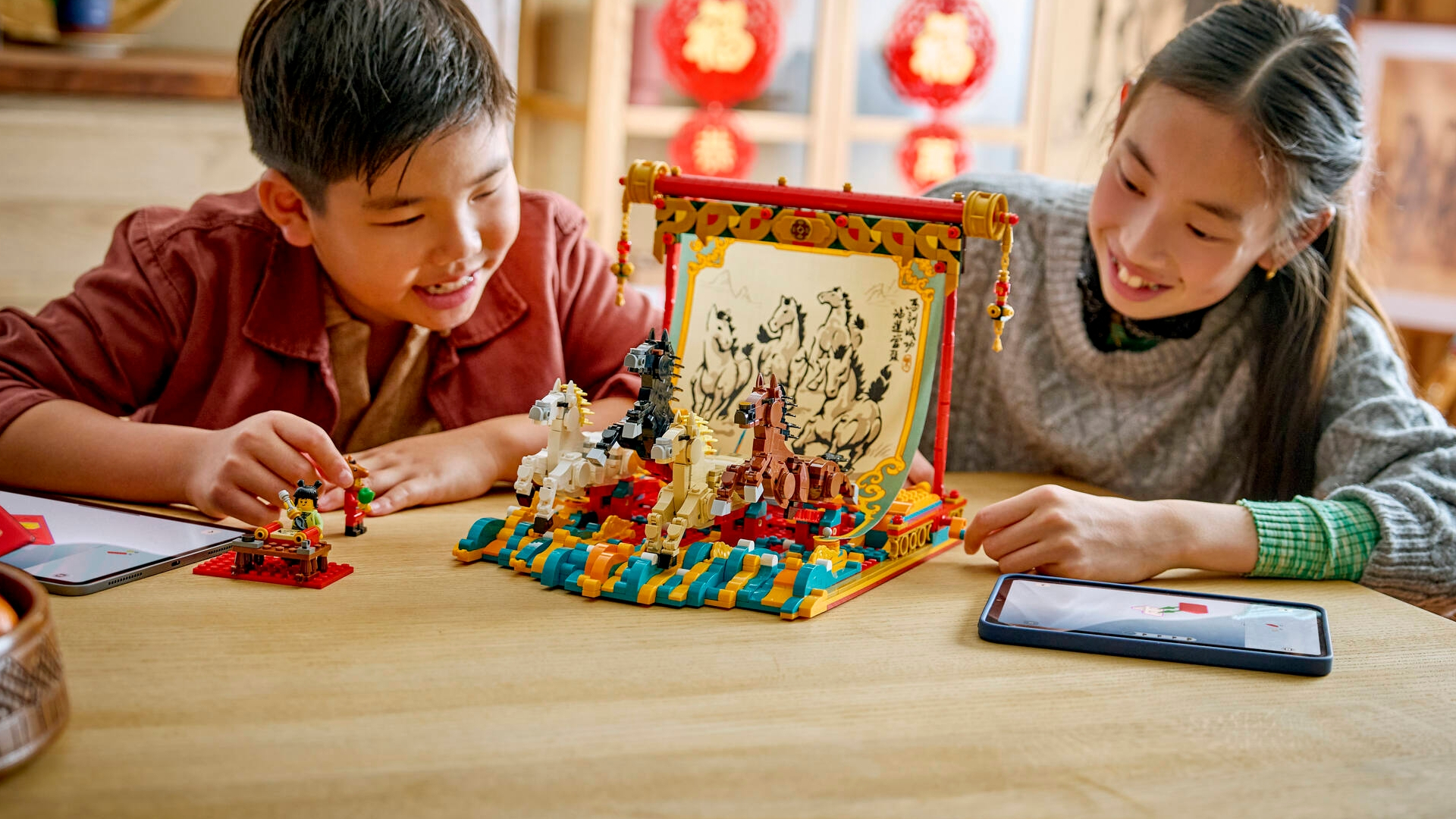 Two children smile and look at the Lego Galloping Horses Canvas on a table