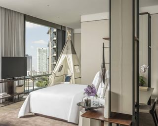 A Four Seasons hotel room with large mattress, TV and children's teepee bed