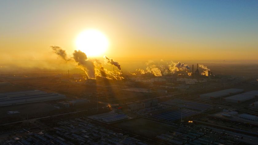 A large, yellow sun is pictured shining close to the horizon over an industrial region of China as smoke from industry pours into the air to reflect the light. 
