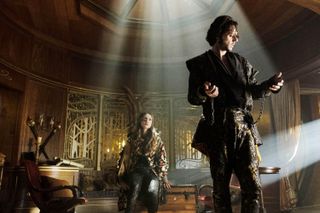 Summer Bishil and Hale Appleman stand in a mystical looking room in fantastical clothing in a still from the magicians season 3