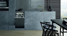 the best slimline dishwasher – the MIELE G4782 slimline dishwasher – in a black and grey stylish kitchen with slate worktops and gold tap, and a black dining table and chairs to the right
