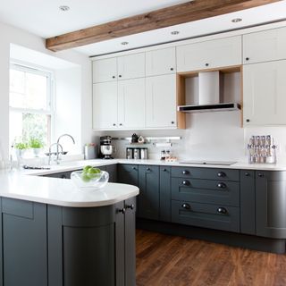 White kitchen with dark grey cabinetry and wooden flooring