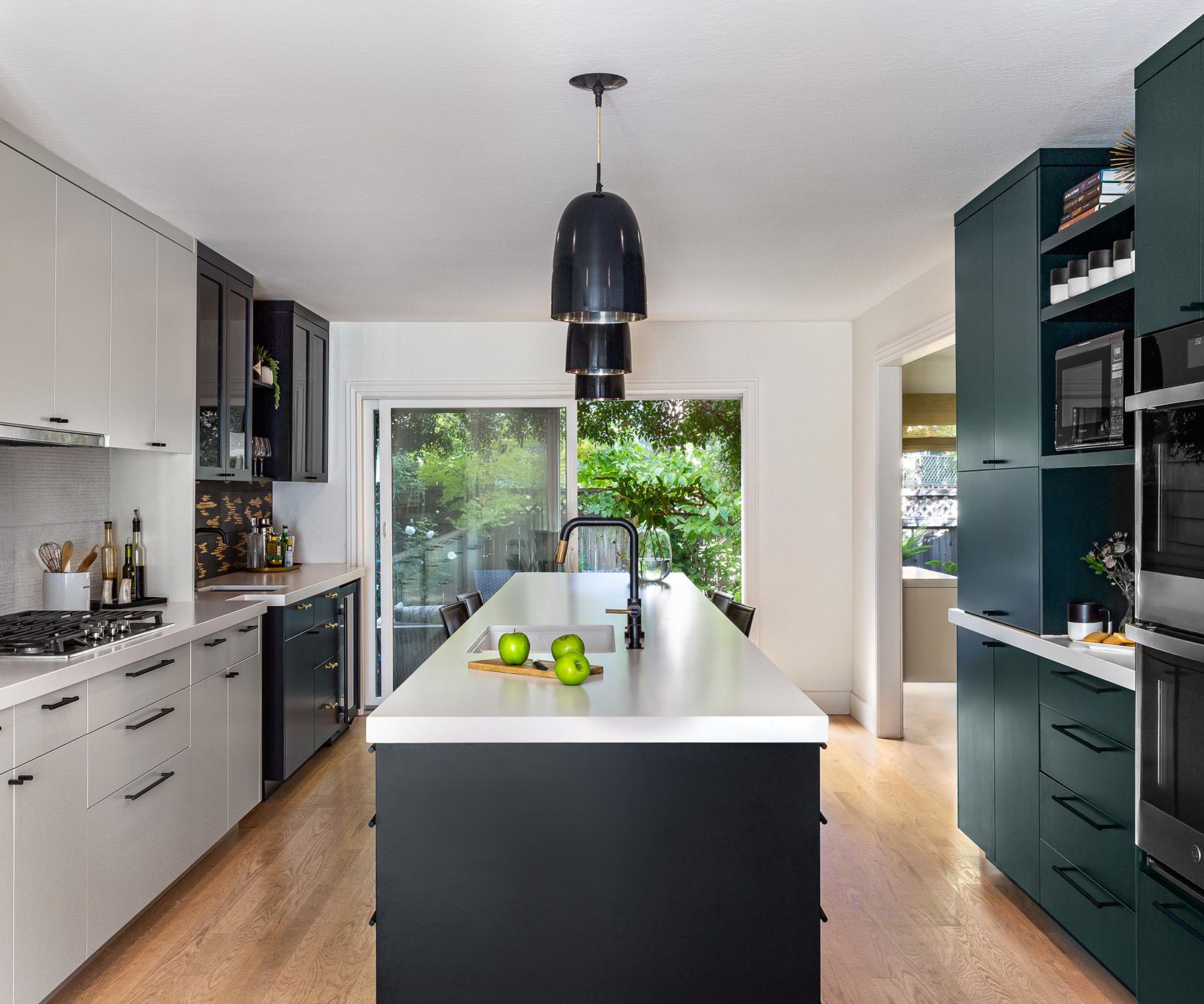 A kitchen with a mix of white and dark green cabinetry
