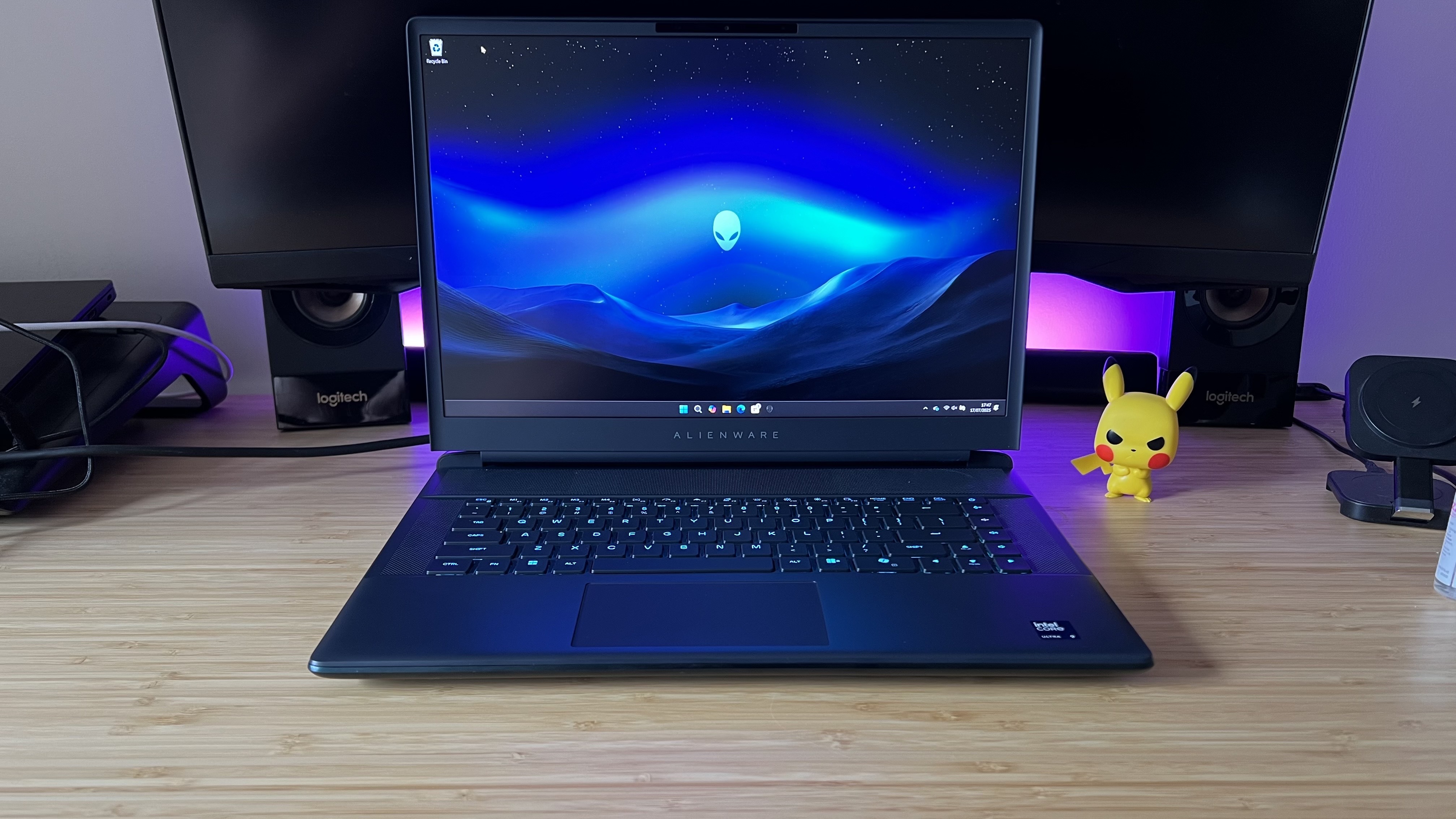 Alienware 16 Area-51 gaming laptop on a wooden desk with purple backlighting