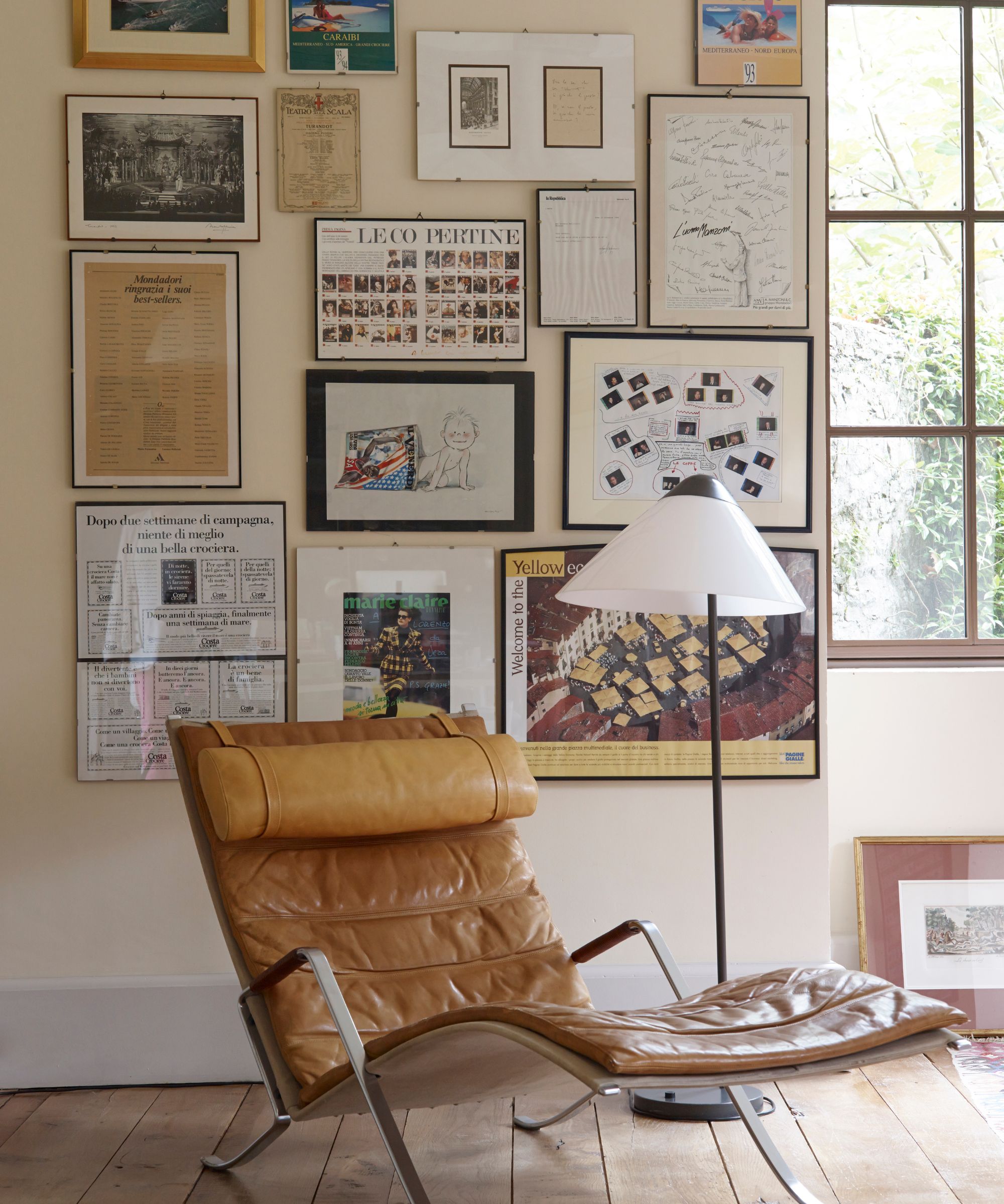 Living room with wooden floors, gallery wall of vintage prints, midcentury leather lounger chair and floor lamp