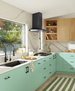 A bright kitchen with patterned wallpaper and turquoise cabinets