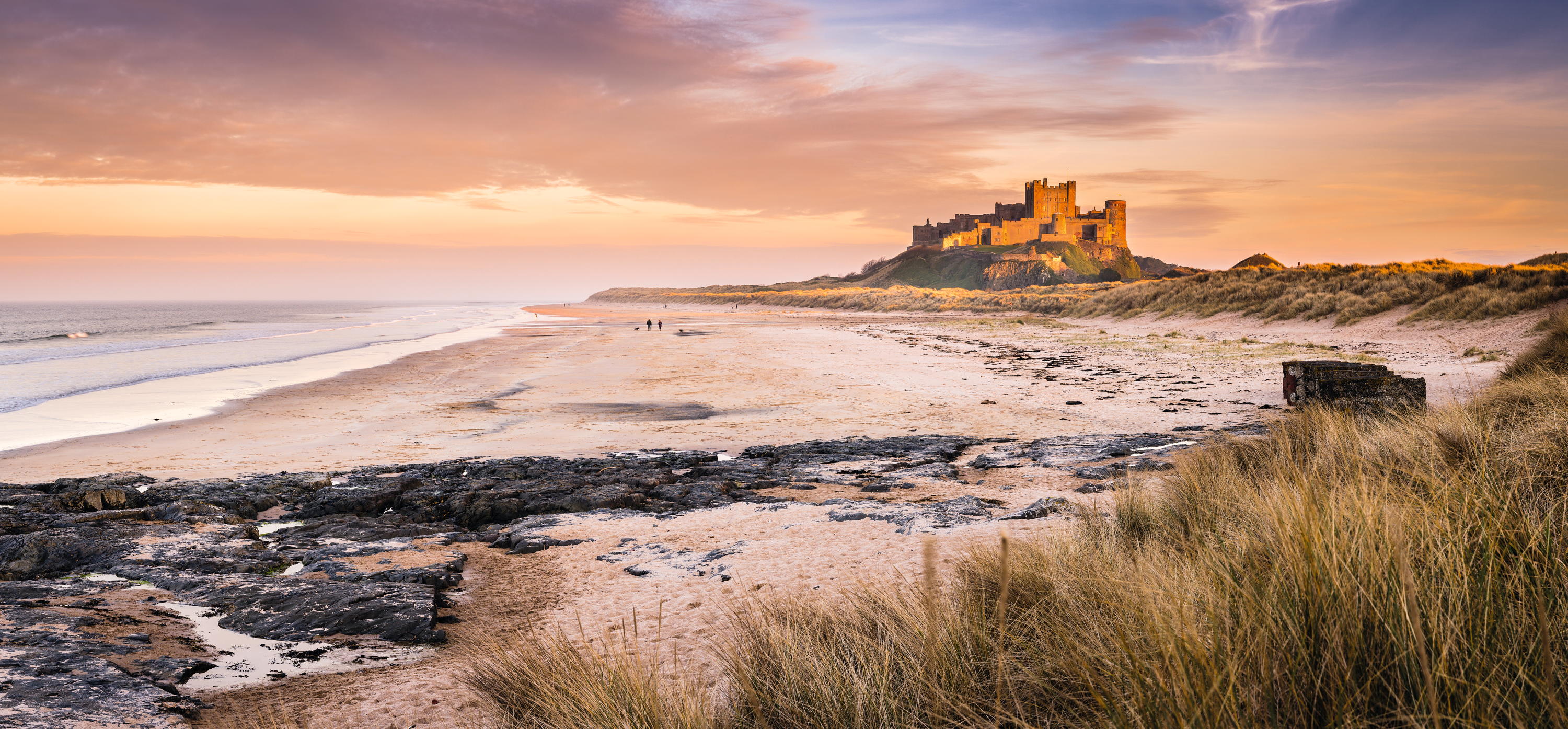 Bamburgh Castle on the Northumberland coastline, bathed in late afternoon golden sunlight