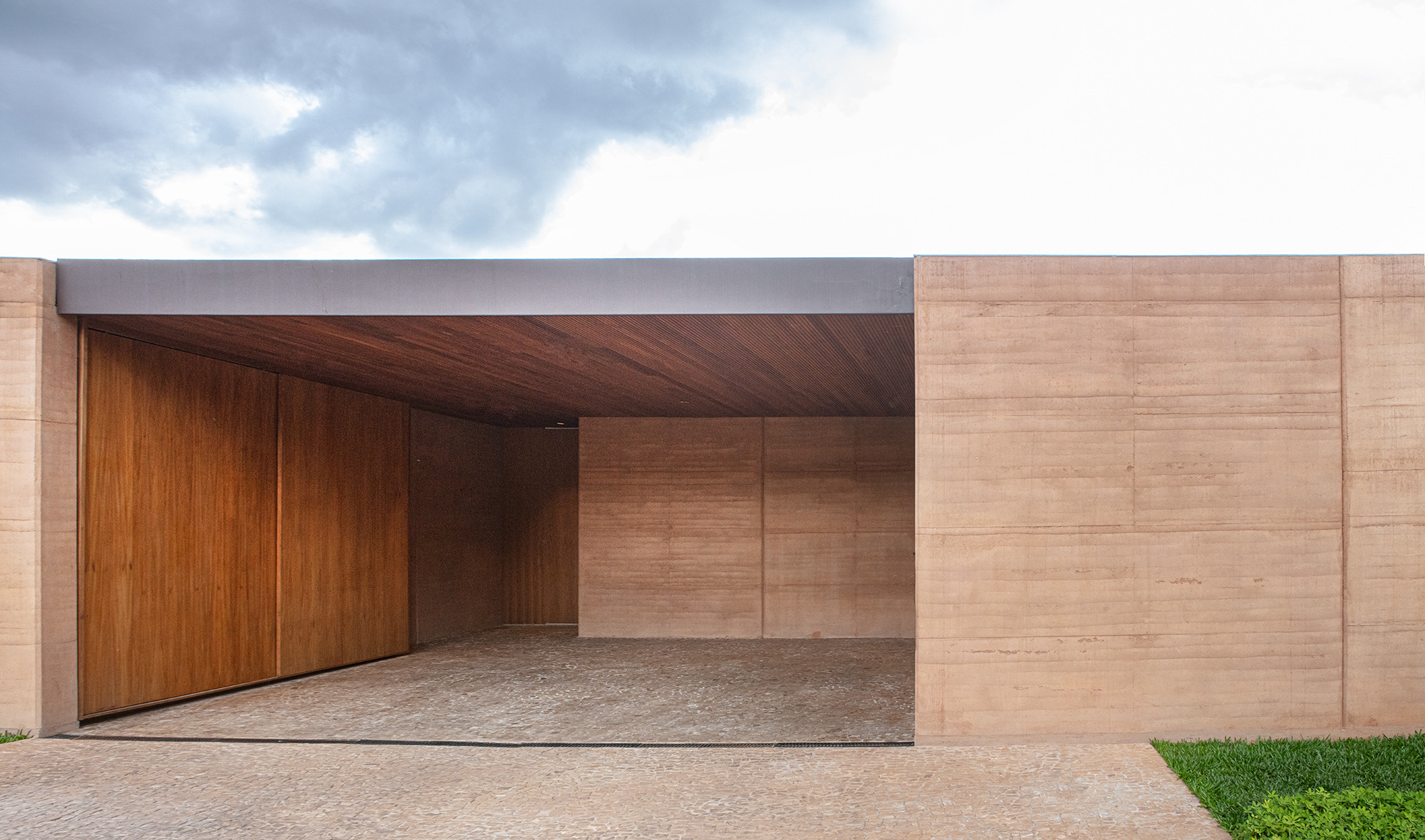 The entrance and car port are formed from meticulously composed rammed earth walls