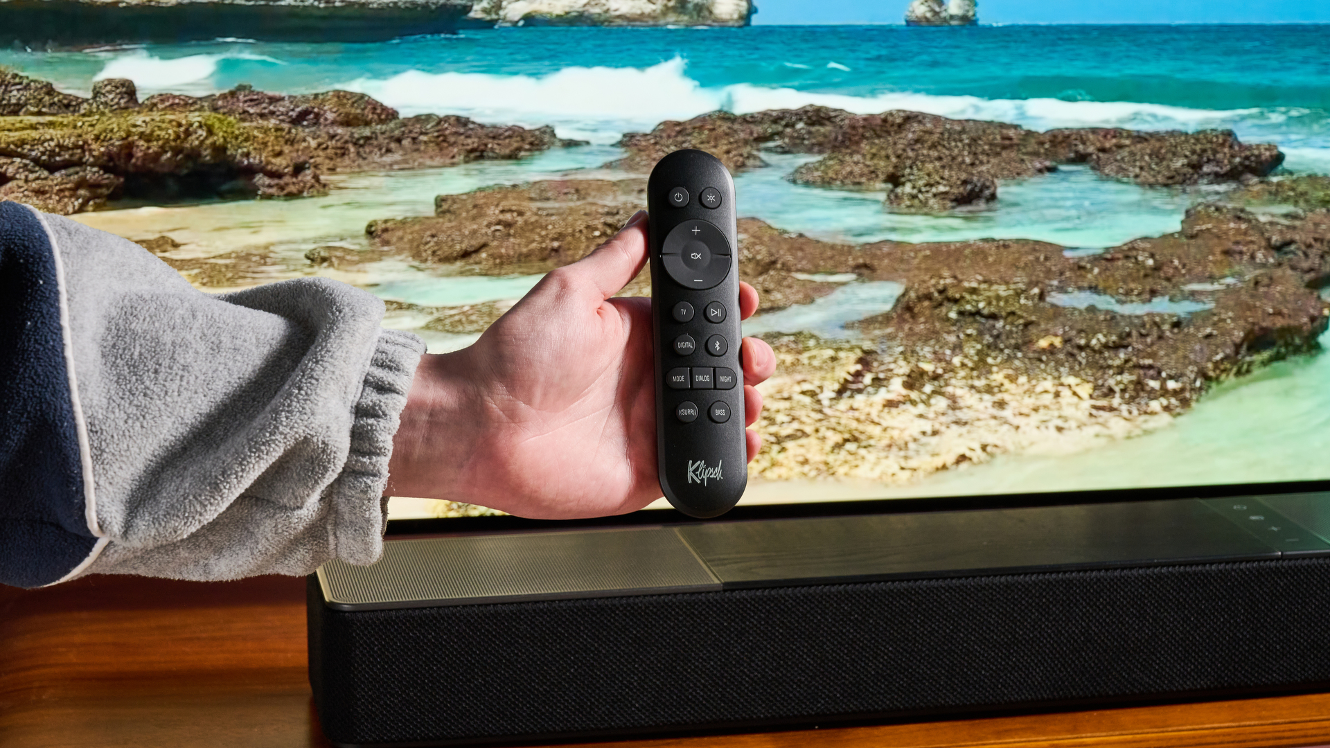 Man holding remote for the Klipsch Flexus Core 100