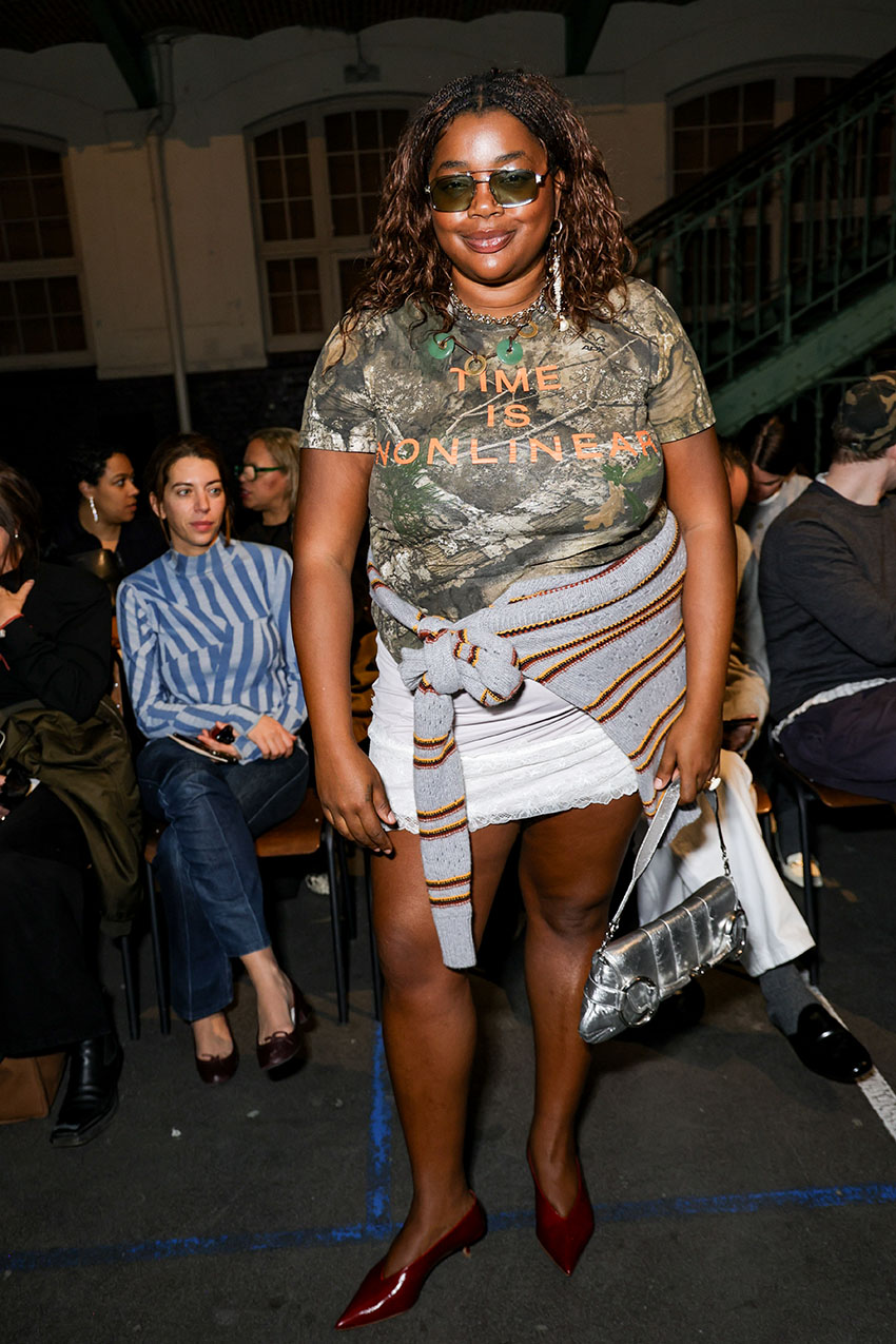 Gabriella Karefa-Johnson wearing a camo t-shirt, white lace skirt, red pointed-toe heels, as striped sweater, and a silver bag.