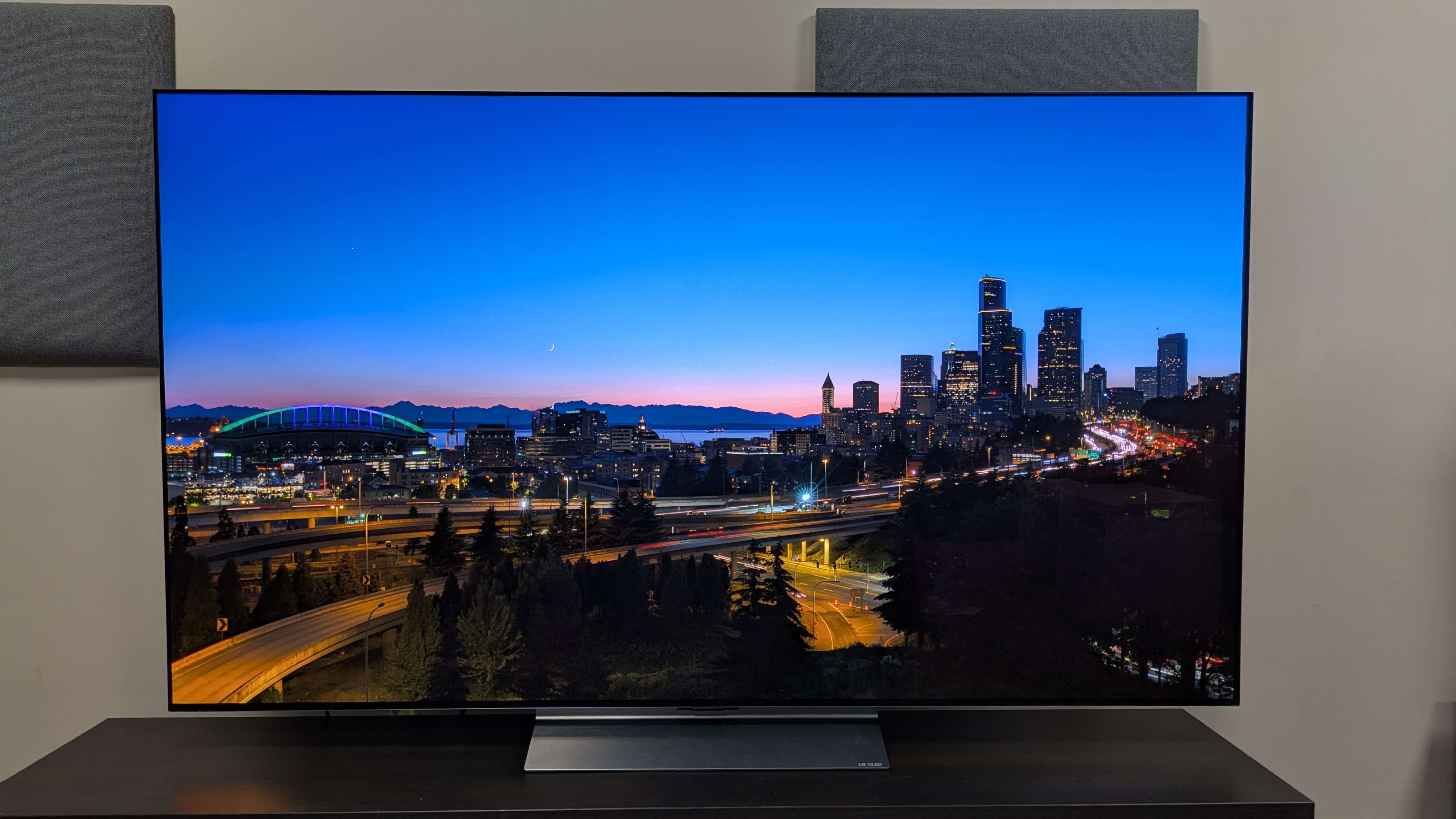 LG C6 with a city skyline on a horizon at sunset on screen
