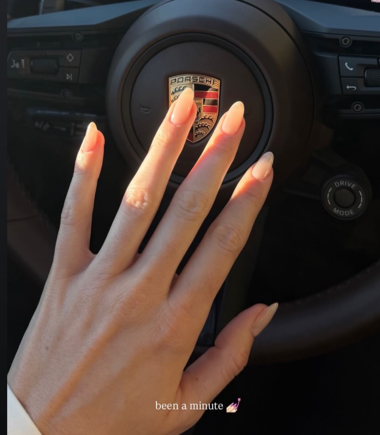 Kendall Jenner's hands with a sheer apricot nail colour on long almond nails