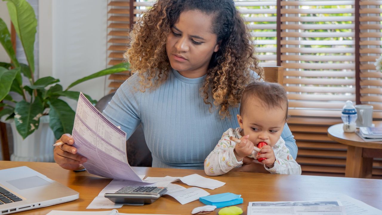 Woman looking at bills while holding baby