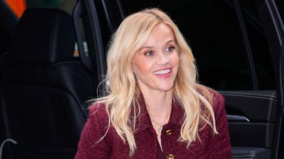 a headshot of reese witherspoon wearing burgundy 