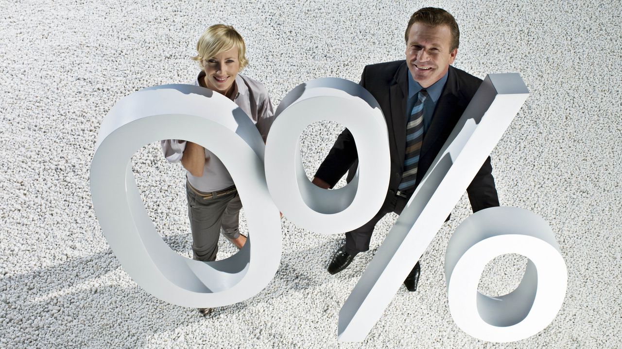 Woman and man holding large 0% sign