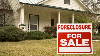 A sign says foreclosed for sale in front of a house.