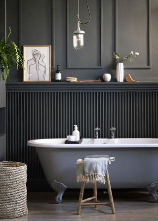 Bathroom with freestanding bath tub and black wood paneling behind the bath