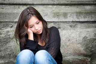 Outdoor portrait of a sad teenage girl looking thoughtful about troubles