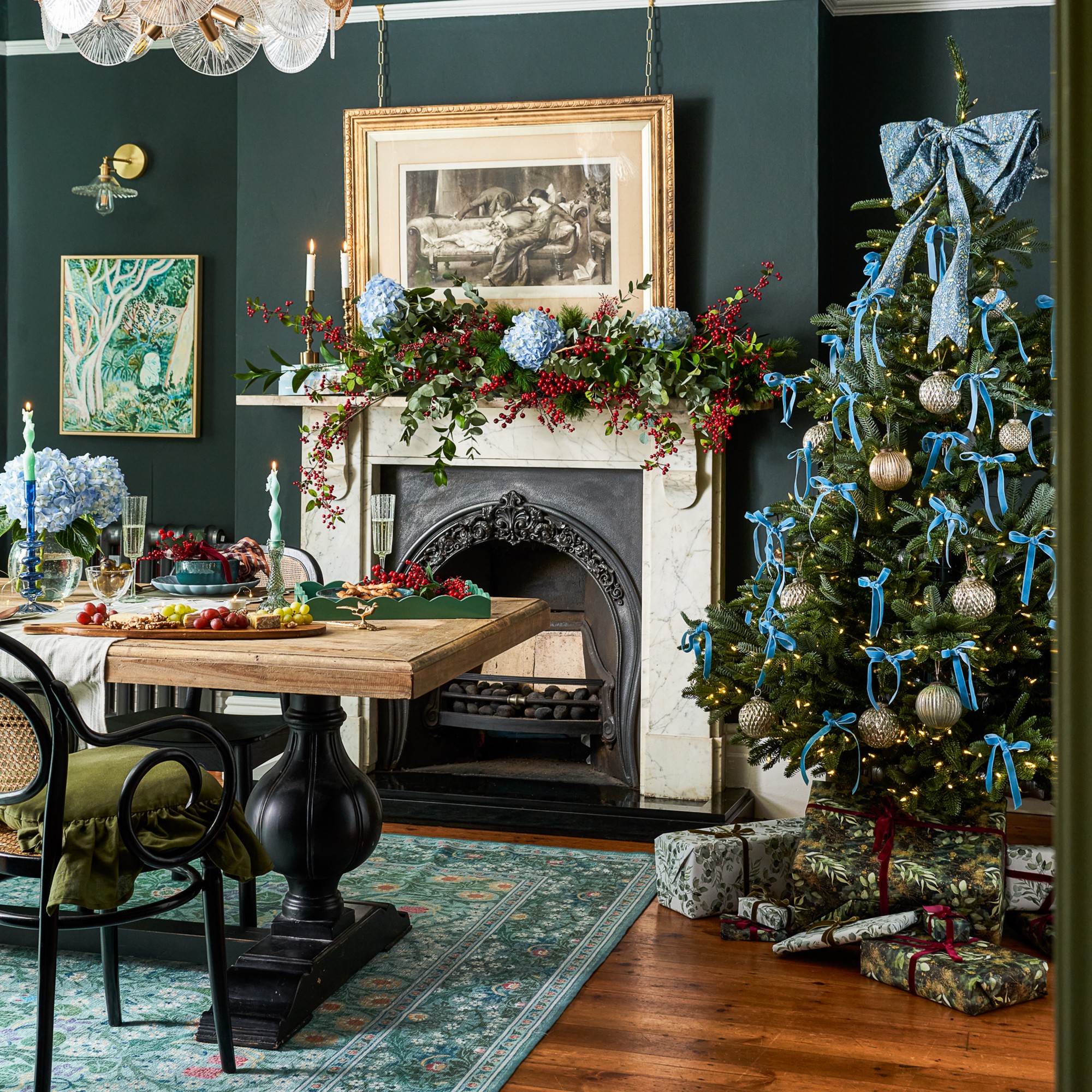 A dining room with a Christmas decorated with blue bows and the table set with a cheese board