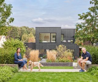 Two home owners sitting in front of their newly completed self build property