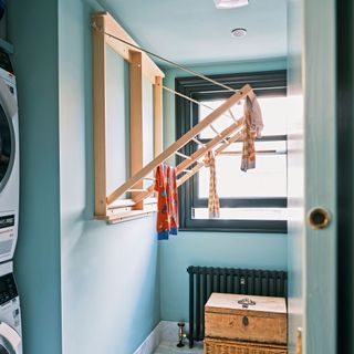blue utility room with washing machine, dryer and airer attached to the wall