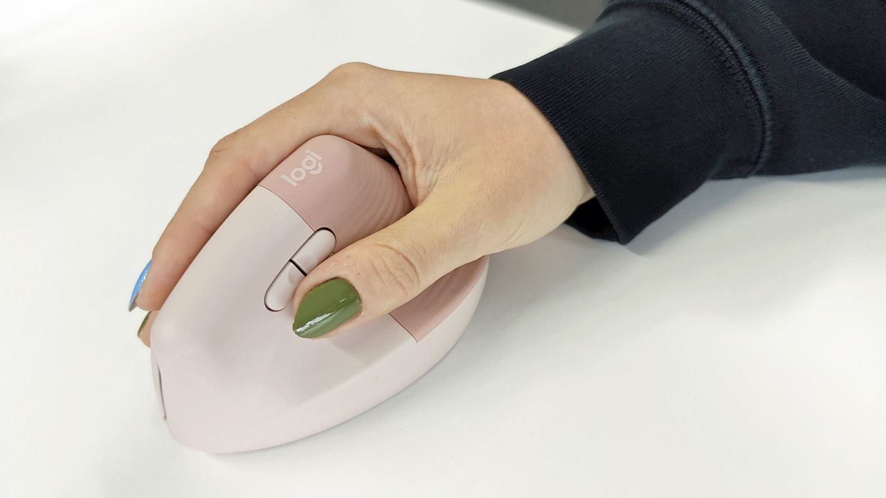 Logitech Lift Vertical Ergonomic Mouse review: woman holding a vertical mouse on a desk