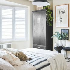 A white bedroom with a black wardrobe and accessories