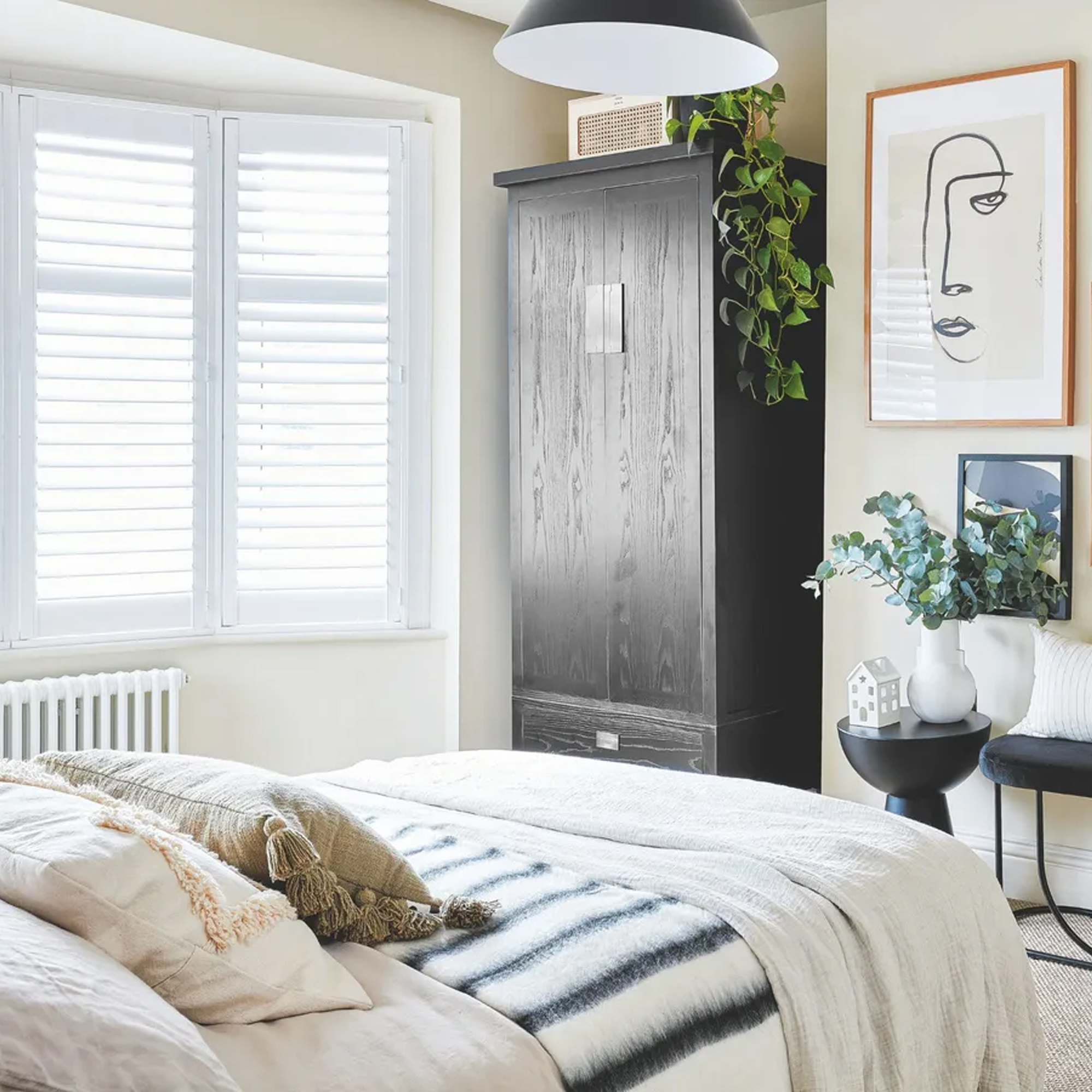 A white bedroom with a black wardrobe and accessories