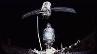 two space station modules are brought together in space using a robotic arm from a space shuttle