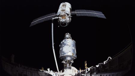two space station modules are brought together in space using a robotic arm from a space shuttle