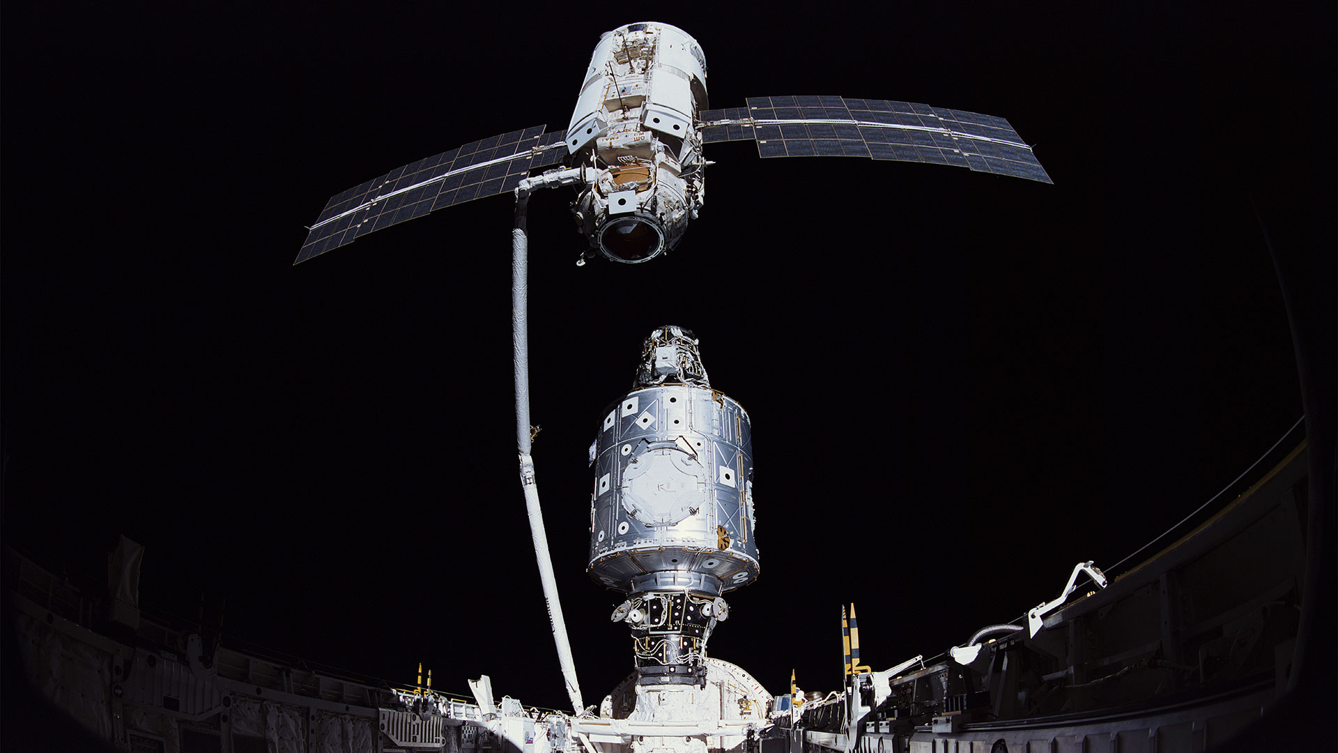 two space station modules are brought together in space using a robotic arm from a space shuttle