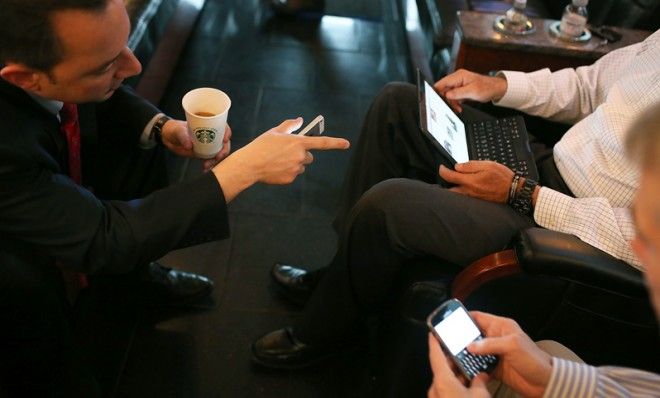 RNC chairman Reince Priebus speaks to Mitt Romney and Rob Portman while they use their respective devices.