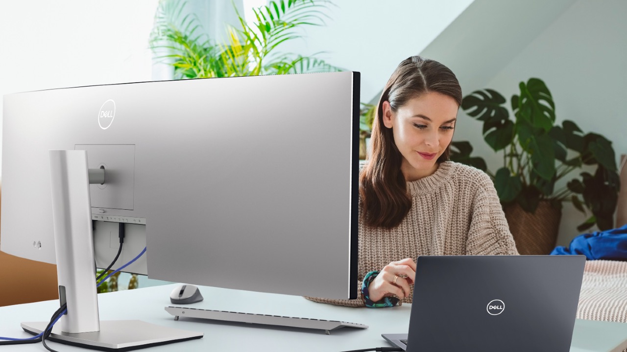 A woman using a Dell laptop and monitor at a desk
