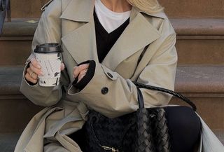 Woman wearing a long tan coat over a black wool sweater and a white tee.