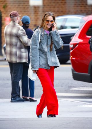 Katie Holmes wears a denim jacket and red trousers