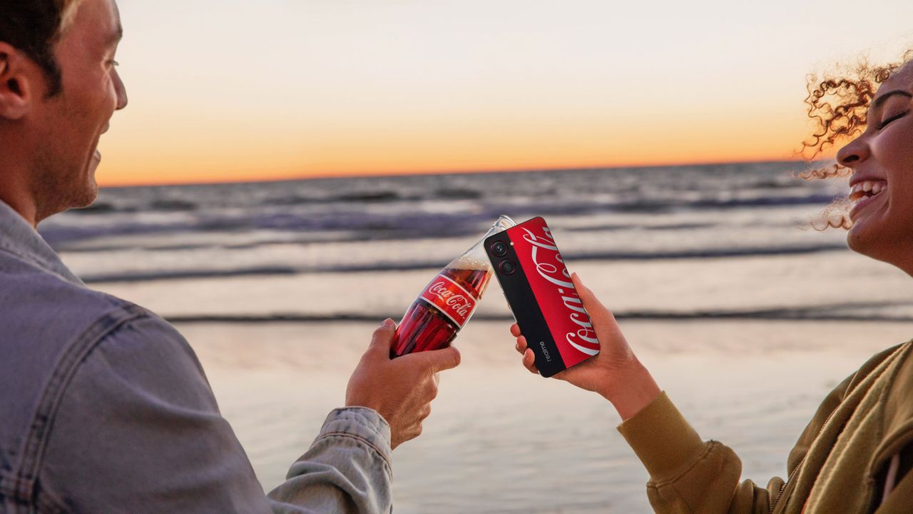 The Realme 10 Pro Coca-Cola limited edition, with a glass bottle of coke at sunset, on the beach